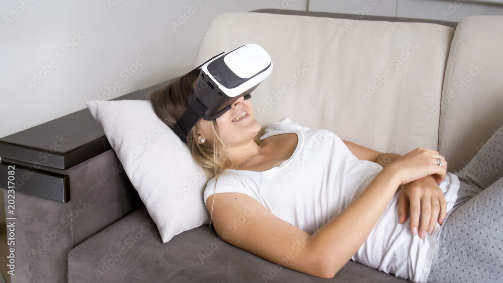 Portrait of happy smiling woman lying on sofa with VR headset Portrait of happy smiling woman lying on sofa with VR headset