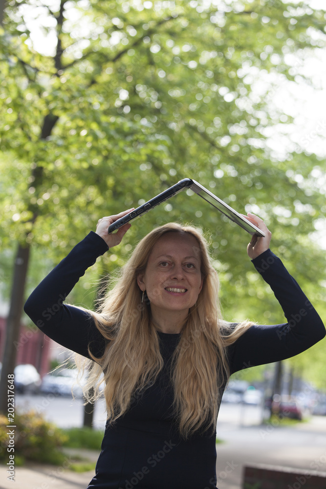 Naklejka premium Smiling woman covering her head with a laptop