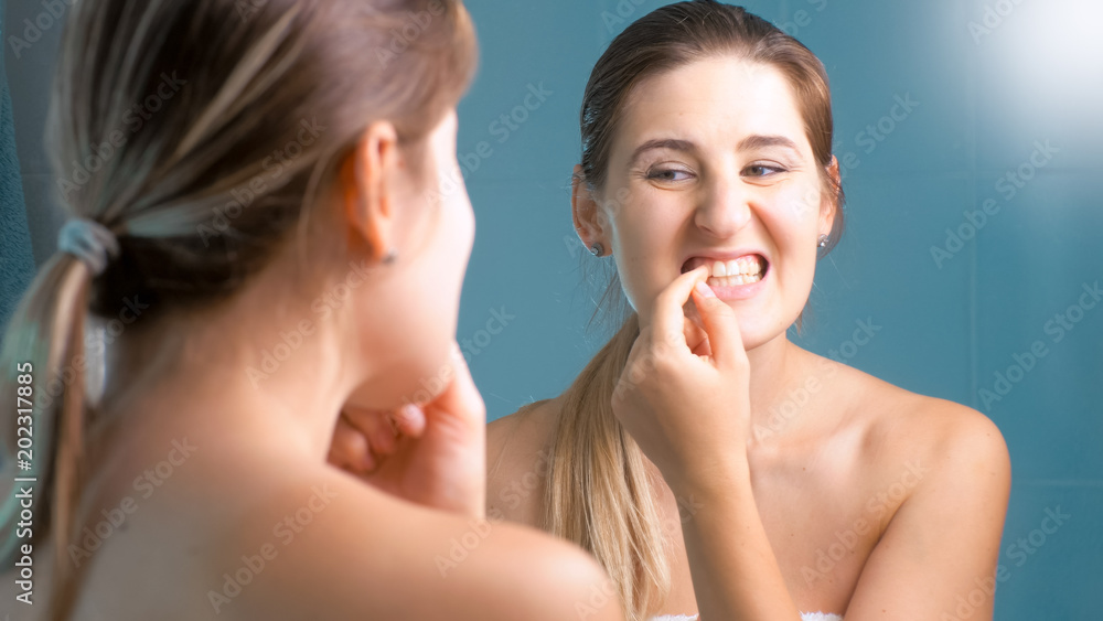 Portrait of young brunette woman trying to take out food stuck in teeth Portrait of young brunette woman trying to take out food stuck in teeth
