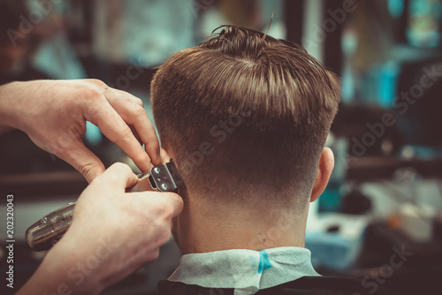 Confident guy sitting at beauty salon . Man haircut. Soft focus.