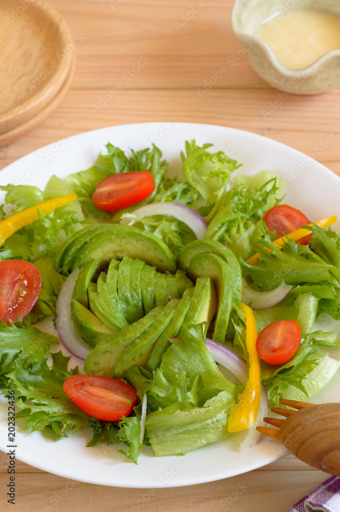 a plate of avocado salad with mayonnaise dressing on wooden background 