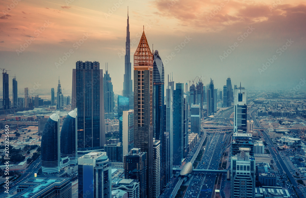 Aerial view on skyscrapers of Dubai, UAE, at sunset. Scenic cityscape with dramatic sky. Travel and architectural background.