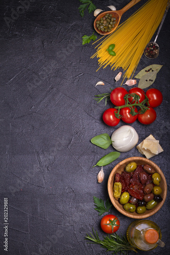 Selection of healthy food. Italian food background with spaghetti, mozzarella parmesan cheese, olives, tomatoes and rosemary. Vegetarian food banner. overhead, vertical