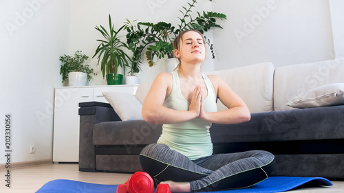 Young relaxed woman in sportrs clothes practicing yoga at home photo