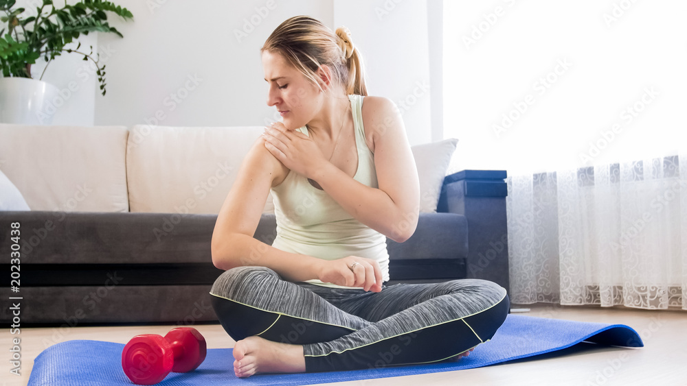 Fototapeta Young woman feeling pain in hand after exercising at home