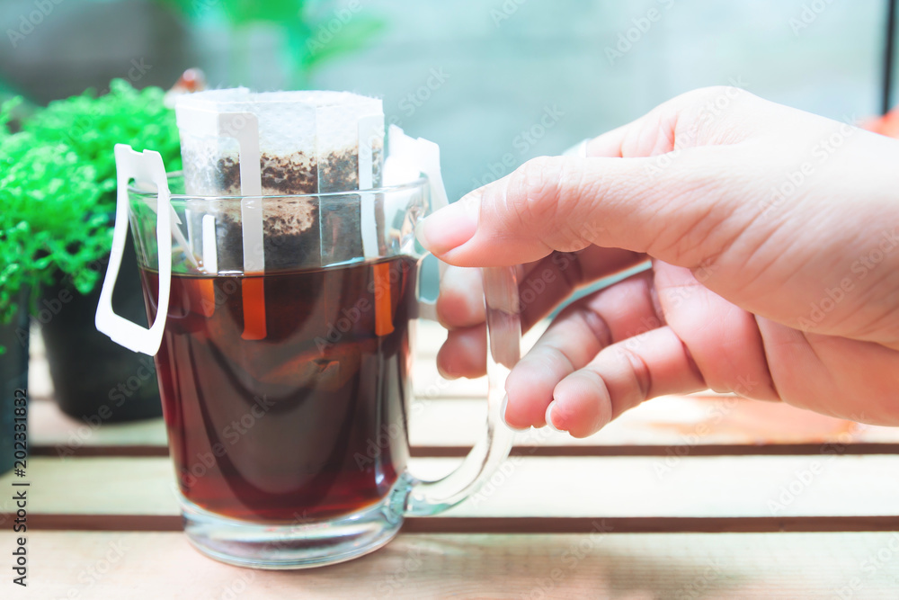 Φωτογραφία Close up woman's hand with a glass of drip coffee,Drip bag fresh coffee with gar