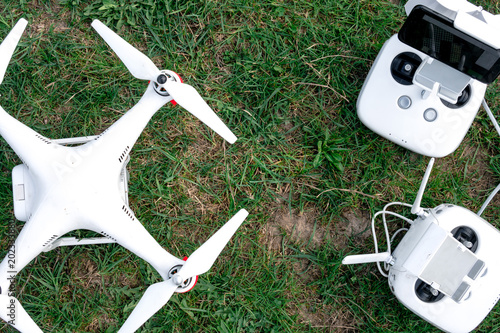 Top view of a flying white professional quadcopter drone camera with green grass in background, aerial photographer equipment, aircraft, rc, remote controller, transmitter photo