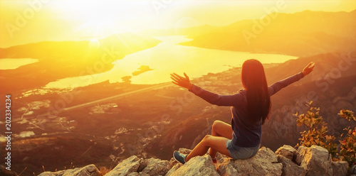 Happy woman in the mountains looking at the sunset