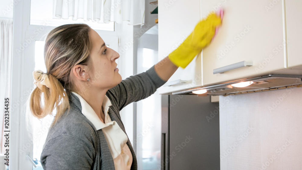 Φωτογραφία Portrait of beautiful young housewife washing cupboards with cloth