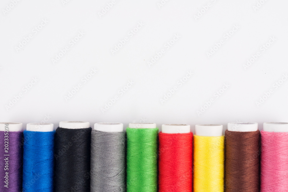 Row of bobbins of new colorful threads on white background. Top view Row of bobbins of new colorful threads on white background. Top view