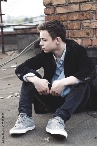 stylish young man sitting on the roof of a building