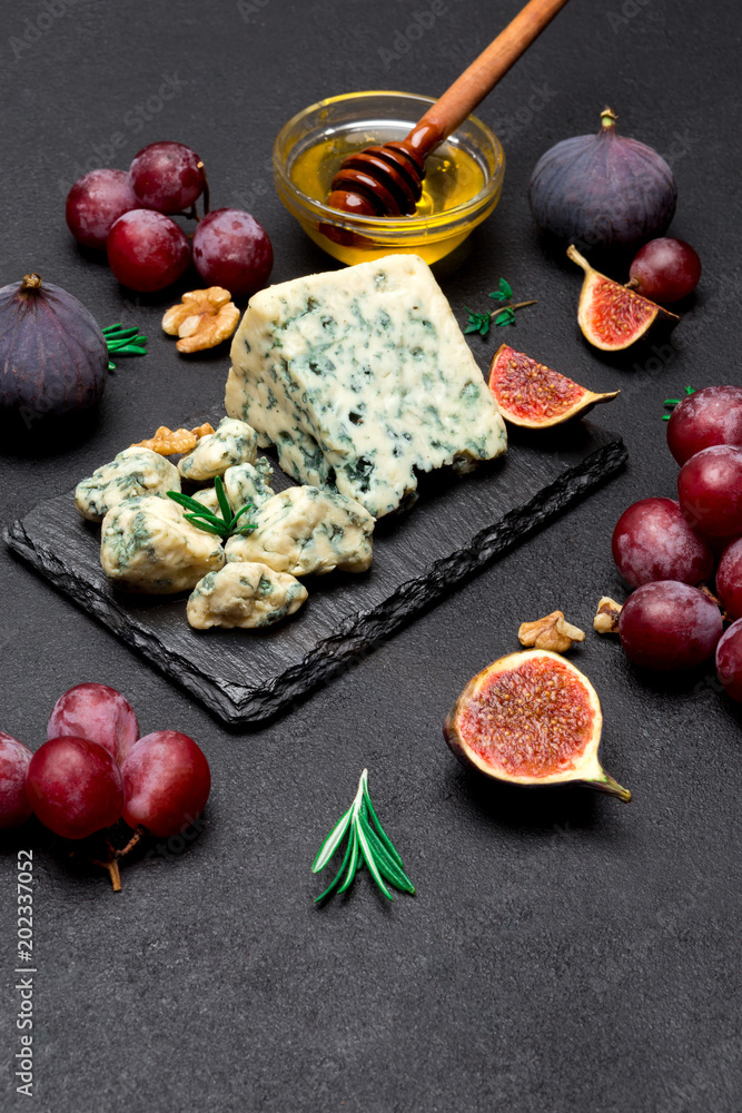 Slice of French Roquefort cheese and fruits on stone board Slice of French Roquefort cheese and fruits on stone board