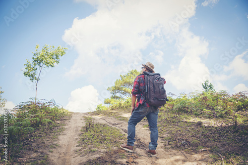 Young Man Traveler with backpack relaxing outdoor with rocky mountains on background Summer vacations and Lifestyle hiking concept.