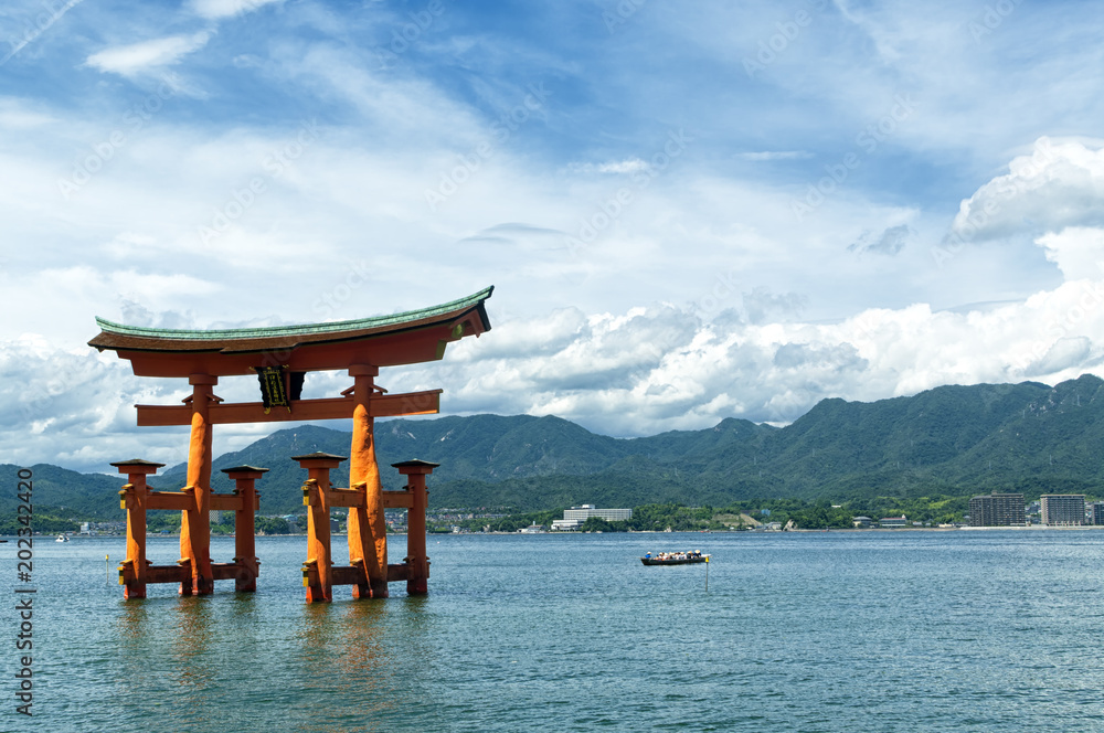 View of the torii (gate) of Itsukushima Shrine at high tide floating in the water of the island of Miyajima, Hiroshima Prefecture, Japan. Unesco World Heritage Site shrine complex