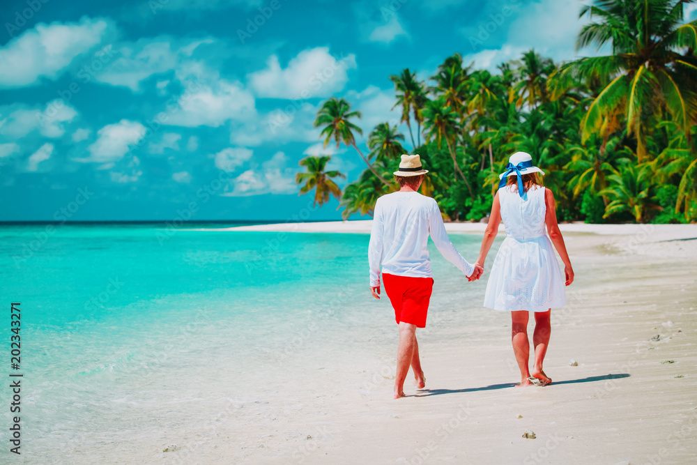 happy loving couple walking on tropical beach