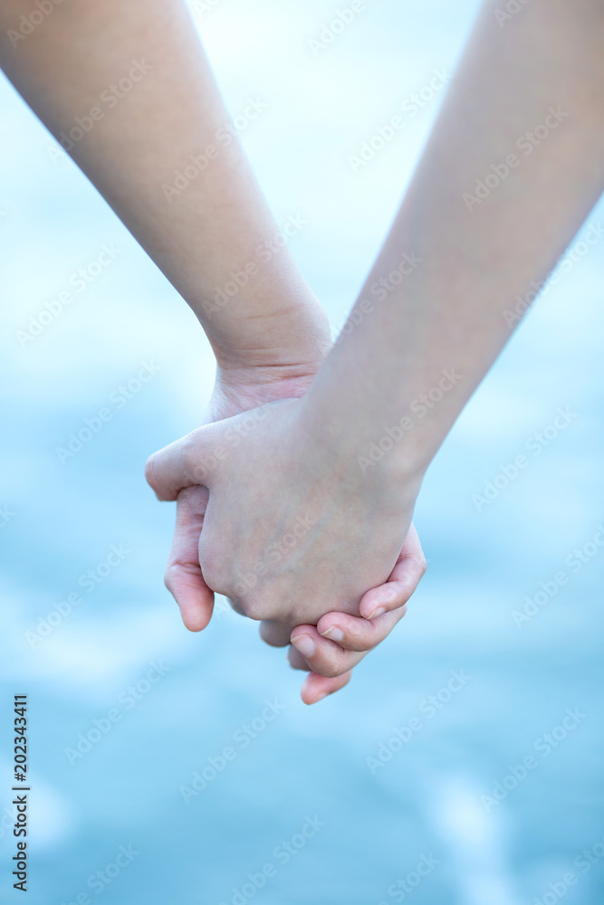 Lovers are holding each other's hands while walking by the sea beach during holiday. Lovers are holding each other's hands while walking by the sea beach during holiday.