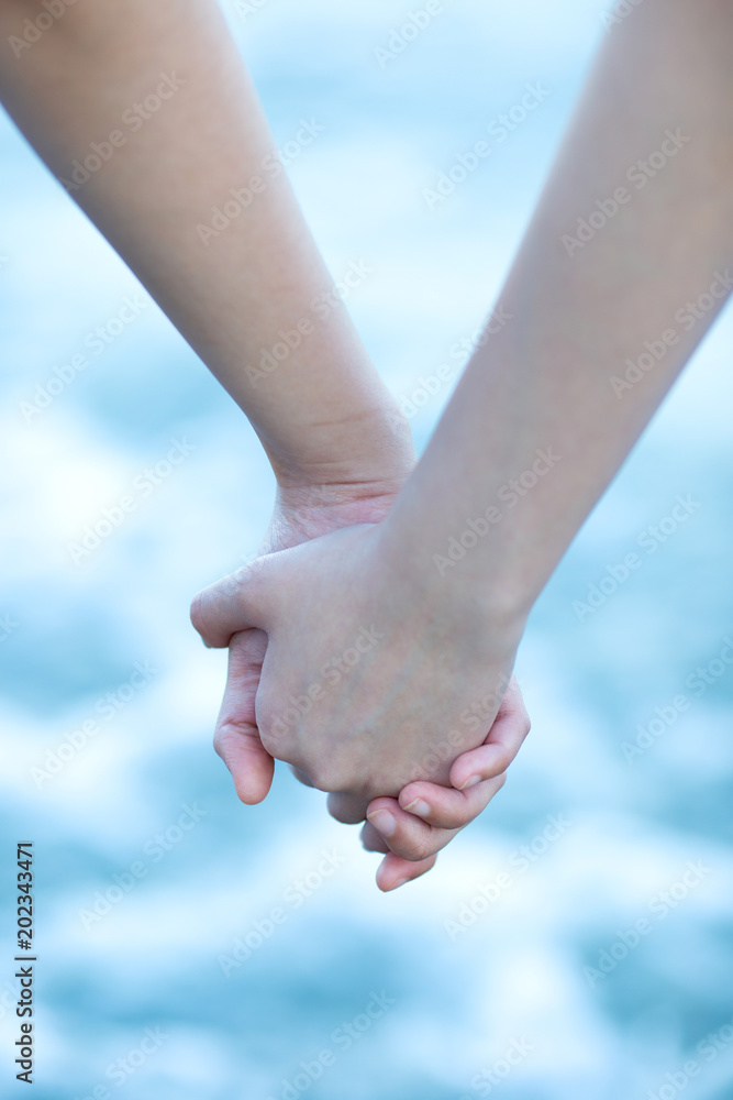 Lovers are holding each other's hands while walking by the sea beach during holiday. Lovers are holding each other's hands while walking by the sea beach during holiday.