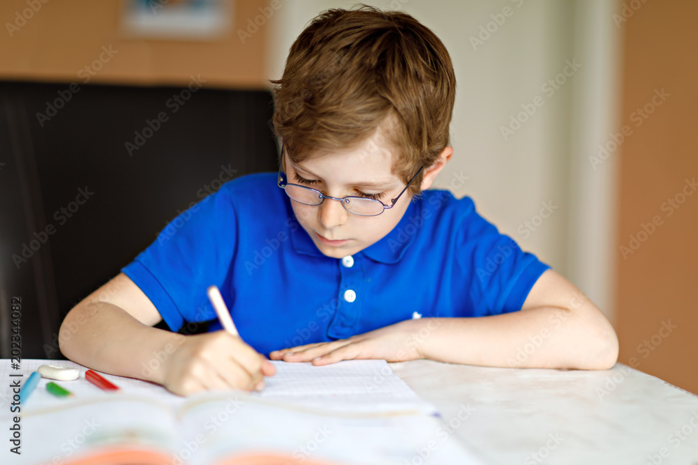 Cute little kid boy with glasses at home making homework, writing letters with colorful pens. Cute little kid boy with glasses at home making homework, writing letters with colorful pens.