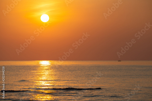 Beautiful sunrise in the morning sky creates its stunning reflection on the sea wave surface.