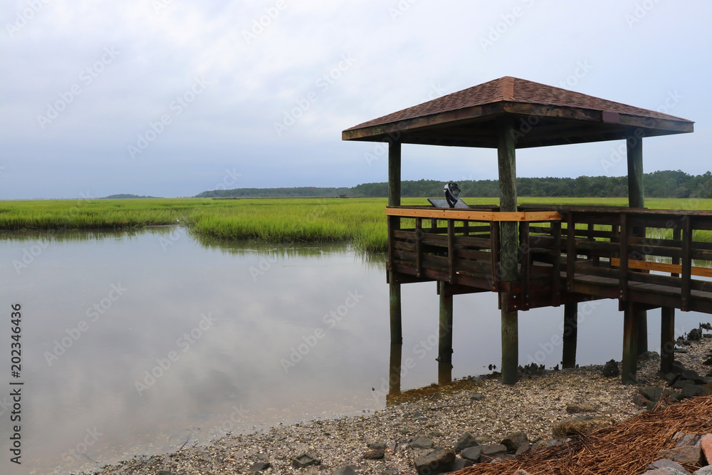 Huntington Beach State Park landscape, South Carolina, USA. Cloudy morning view across the expansive salt marsh with observation point and reflected sky in the calm water.