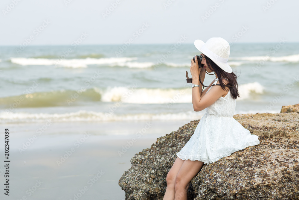 Asian tourist woman taking photo on the beach.