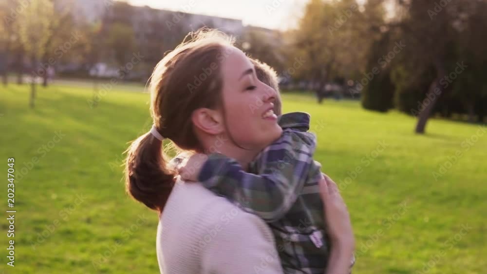 Happy mother hugs little son at sunset in city park Happy mother hugs little son at sunset in city park