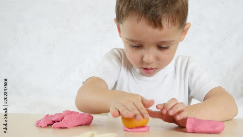 Children's creativity. The baby boy forms the figures from the color test on the table. Cute children's plasticine figures on the table. Children's creativity. The baby boy forms the figures from the color test on the table. Cute children's plasticine figures on the table.