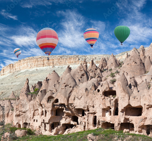 Colorful hot air balloons flying over geological formations in Zelve valley, Cappadocia, Turkey