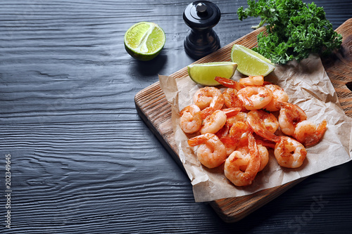 Board with delicious fried shrimps and lime on wooden background
