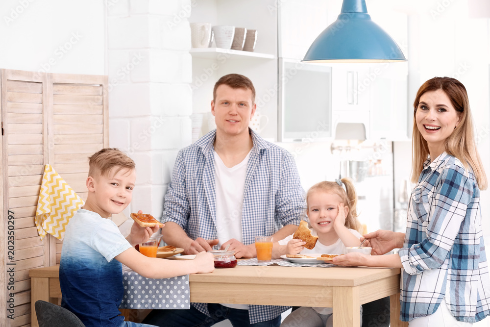 Parents and cute little children having breakfast with tasty toasted bread at table