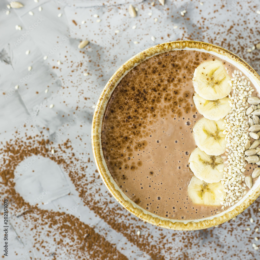 Chocolate-banana smoothies in a bowl on a gray concrete background next to the shape of a spoon of cocoa. Healthy Breakfast Concept Chocolate-banana smoothies in a bowl on a gray concrete background next to the shape of a spoon of cocoa. Healthy Breakfast Concept