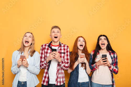 Group of happy school friends holding mobile phones