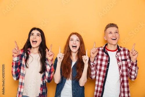 Group of happy school friends pointing fingers up
