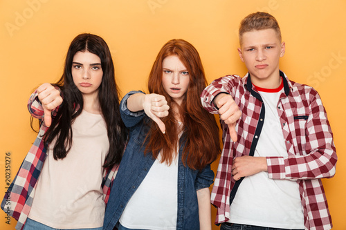 Group of disappointed school friends showing thumbs down