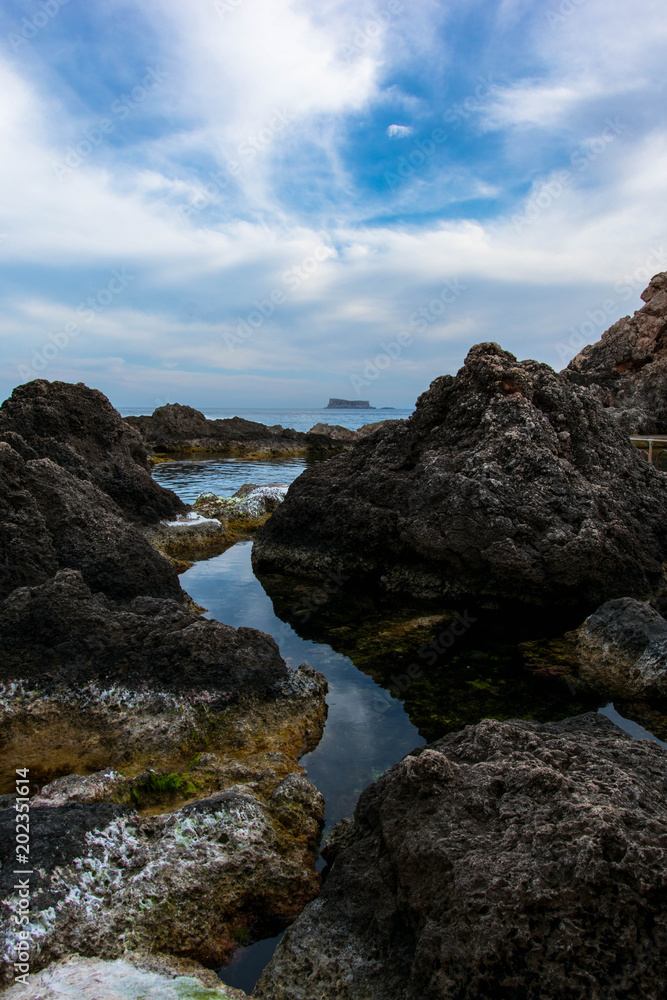Stones with great detail and colors along with a dramatic and cloudy sky and calm sea