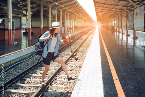 Ladies carrying luggage and cameras are taking a shortcut to the railroad.