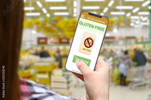 Gluten free diet idea, girl with frameless phone on blurred shop background