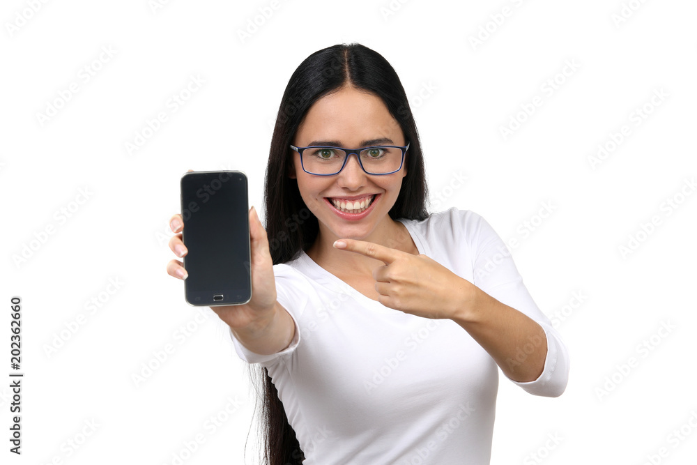 Hübsche dunkelhaarige Frau mit Brille ist begeistert und zeigt auf ein leeres Smartphone Display Hübsche dunkelhaarige Frau mit Brille ist begeistert und zeigt auf ein leeres Smartphone Display