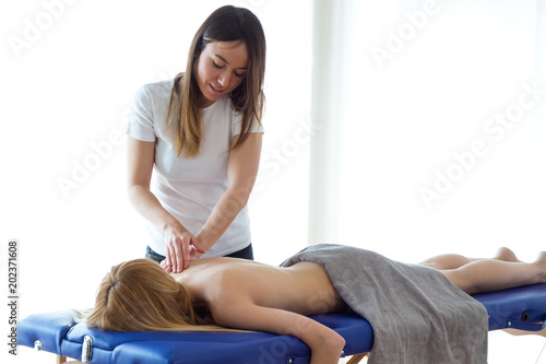 Young physiotherapist doing a back treatment to the patient in a physiotherapy room.
