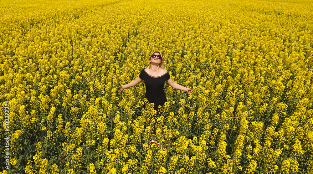 Φωτογραφία A girl in a black dress among the colors of rape in the field