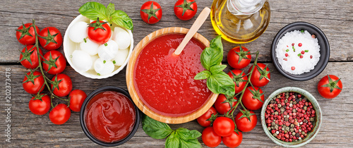 Fotografie Ingredients for cooking - tomato sauce, pasta, tomatoes, garlic, olive oil on the old wooden background