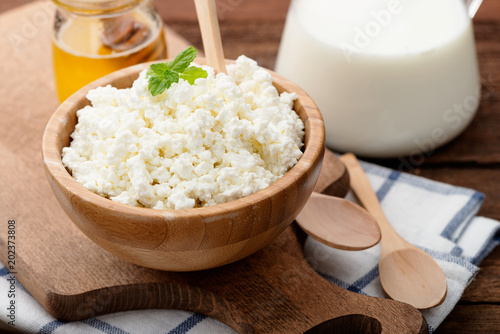 Homemade cottage cheese in a wooden bowl on dark wooden background. 