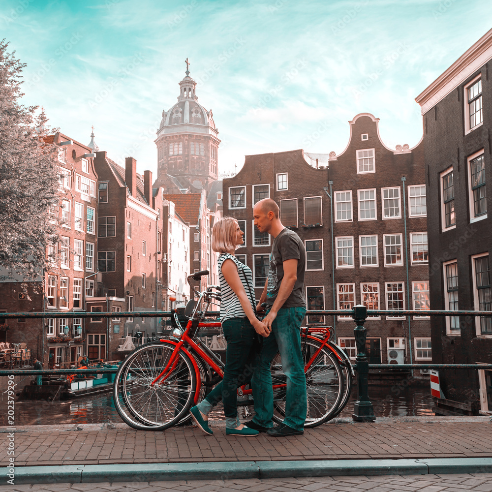 Φωτογραφία Two lovers person in Amsterdam on a background of multi-colored house in the Dutch style stand and hold hands