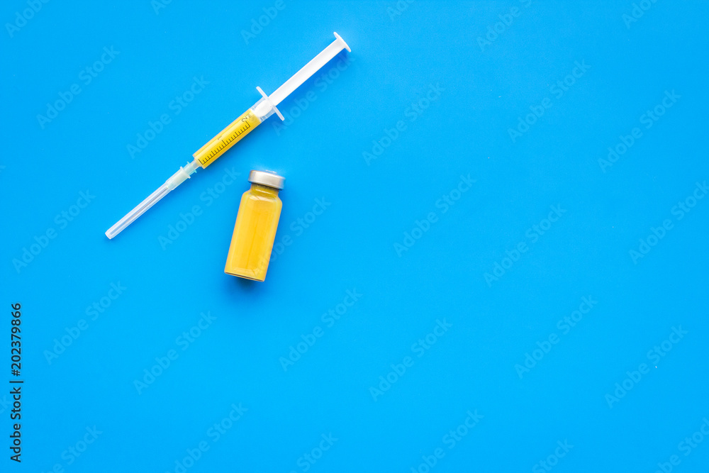 Medical injection. Syringe and bottle with remedy on blue background top view copy space Medical injection. Syringe and bottle with remedy on blue background top view copy space