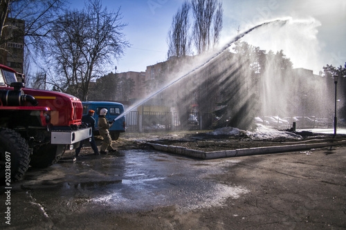 Firefighter and emergency situations mimic the fire on the background of a fire truck on a Sunny day.