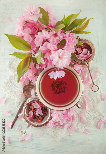 vintage, antique cup of fruit tea decorated with cherry flowers on white background in a shabby chic look