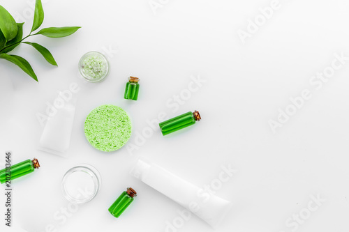 Natural cosmetics for skin care near green leaves on white background top view copy space