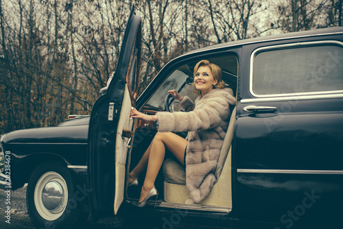 Travel and business trip or hitch hiking. sexy woman in fur coat. Escort and security guard for luxury woman. Call girl in vintage car. Retro collection car and auto repair by driver