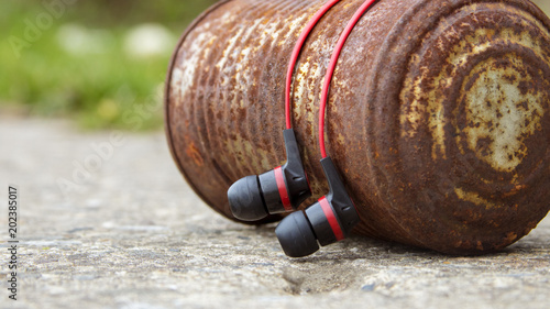 Earbuds draped over a vintage can. 