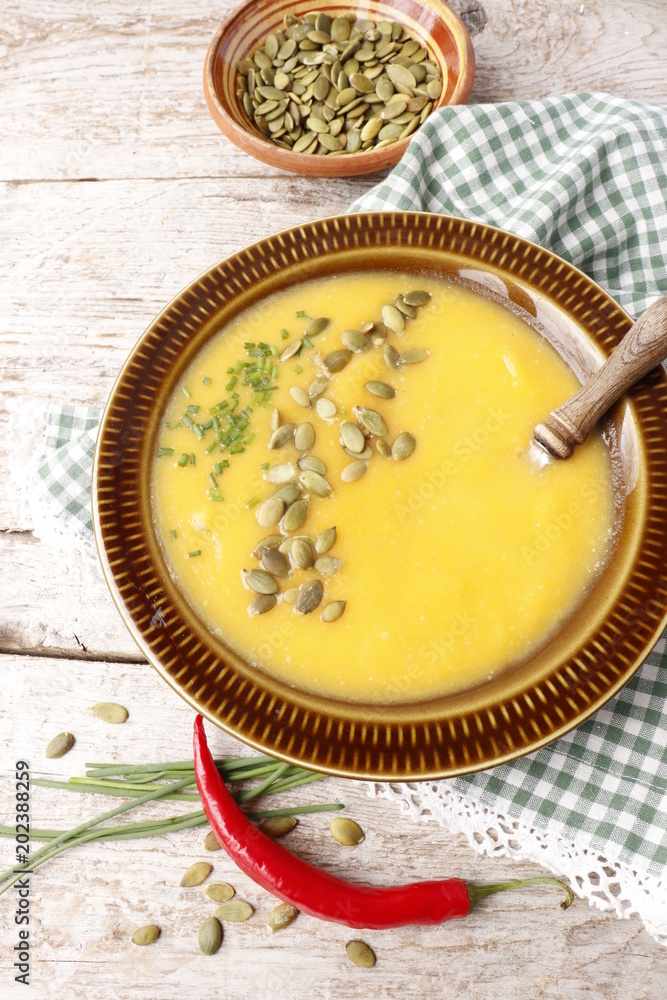 Pumpkin soup puree in a bowl, sprinkled with pumpkin seeds and chopped chives onions. Pumpkin soup puree in a bowl, sprinkled with pumpkin seeds and chopped chives onions.
